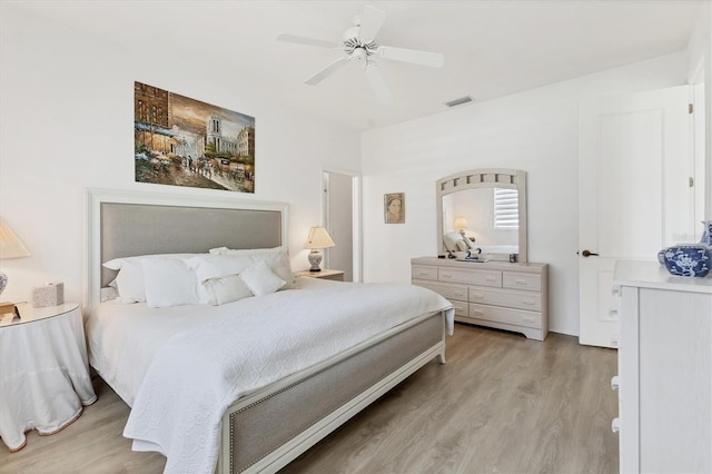 bedroom featuring light wood finished floors, visible vents, and a ceiling fan