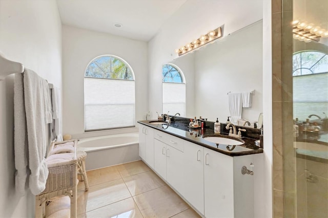 full bath featuring a sink, a garden tub, double vanity, and tile patterned flooring