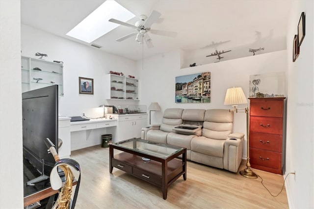 living room featuring a skylight, visible vents, light wood-style floors, and ceiling fan