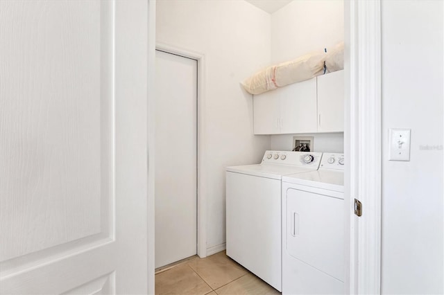 washroom featuring washing machine and clothes dryer, cabinet space, and light tile patterned flooring