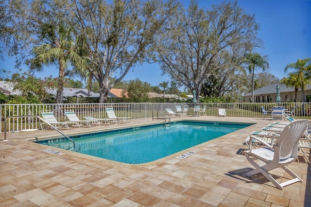 community pool with a patio area and fence