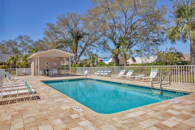 community pool with a patio area and fence