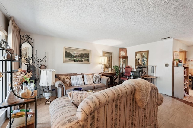 living area featuring light tile patterned floors, visible vents, and a textured ceiling