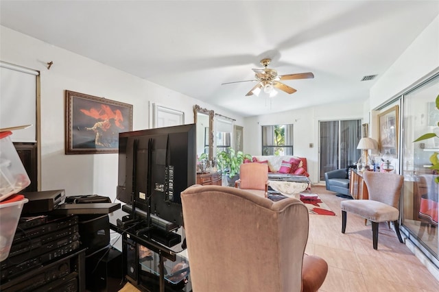 living area with light tile patterned floors, visible vents, and ceiling fan