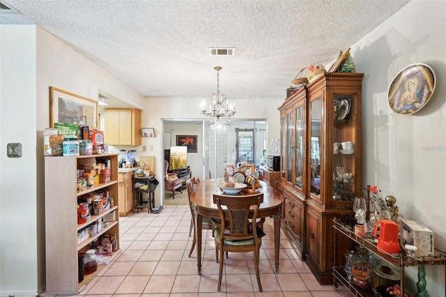 dining room featuring light tile patterned floors, visible vents, a notable chandelier, and a textured ceiling