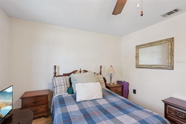 bedroom featuring visible vents, a textured ceiling, and ceiling fan