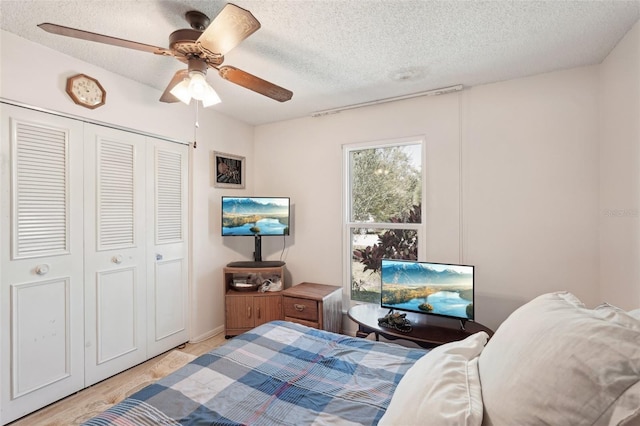 bedroom with light wood-type flooring, a textured ceiling, a closet, and ceiling fan