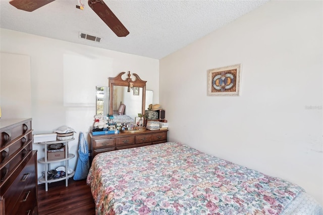 bedroom with ceiling fan, visible vents, a textured ceiling, and dark wood finished floors