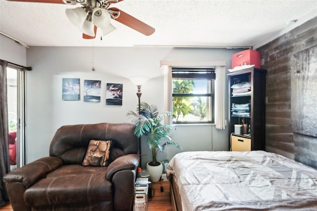 bedroom with a textured ceiling, a ceiling fan, and wood finished floors