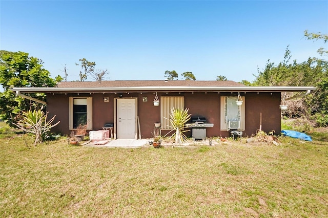 rear view of property featuring stucco siding and a lawn