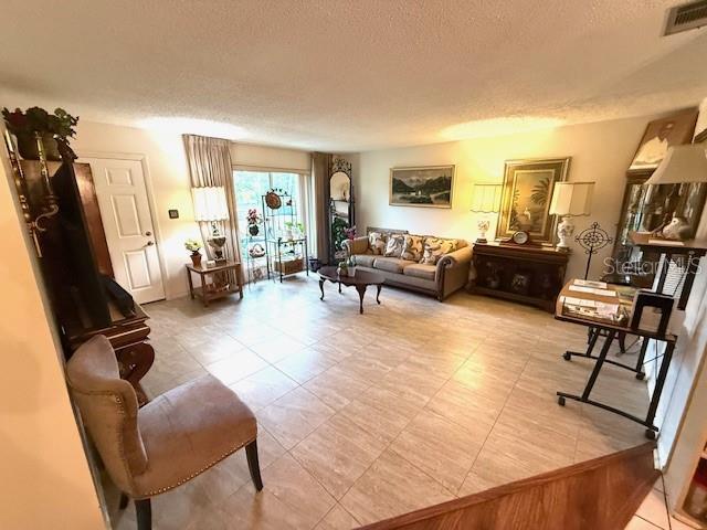 2678 Rock Creek Dr, Port Charlotte, FL 33948 - living room with a textured ceiling and light tile patterned flooring