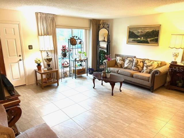 2678 Rock Creek Dr, Port Charlotte, FL 33948 - living room with a textured ceiling and light tile patterned flooring