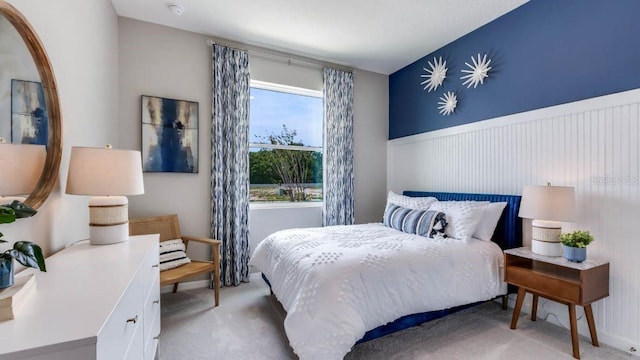 bedroom with light carpet and wainscoting