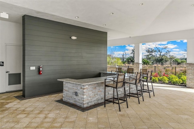 view of patio featuring outdoor dry bar and fence