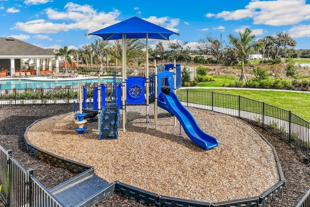 communal playground with a community pool, fence, and a lawn