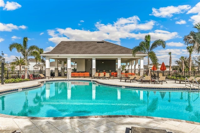 pool featuring an outdoor structure, a patio, and fence