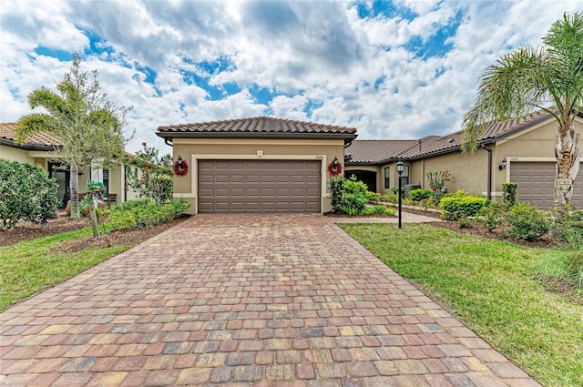 mediterranean / spanish home with stucco siding, decorative driveway, an attached garage, and a tile roof