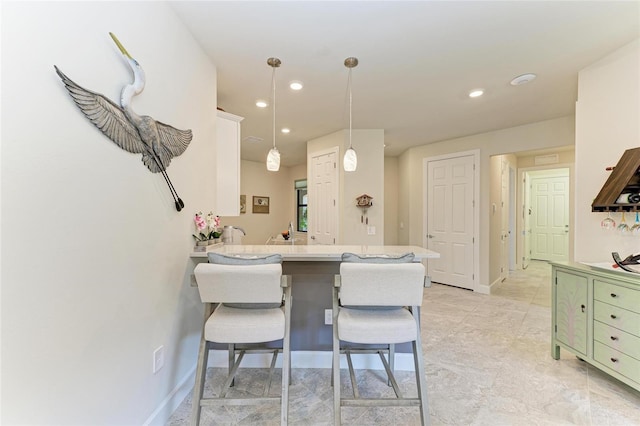 kitchen with baseboards, pendant lighting, a breakfast bar, recessed lighting, and a peninsula