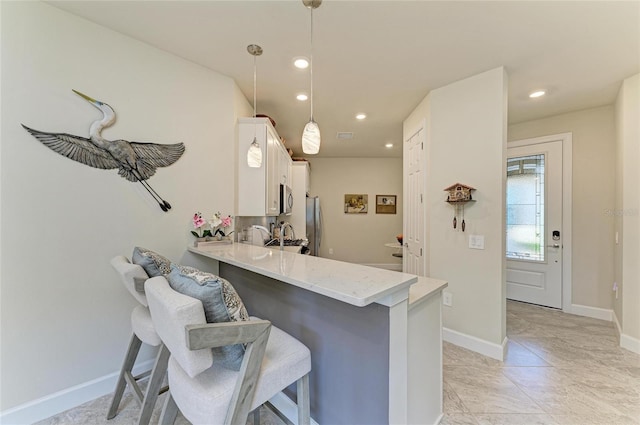 kitchen with recessed lighting, a peninsula, a breakfast bar area, white cabinets, and baseboards