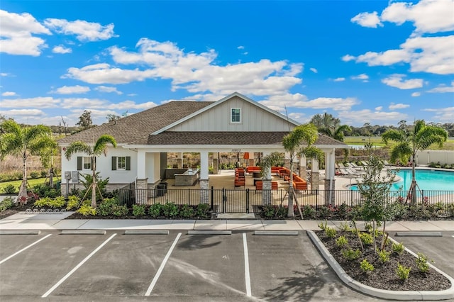 view of property with a community pool, fence, and uncovered parking