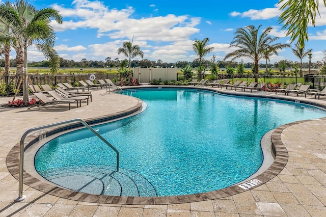 community pool with fence and a patio area