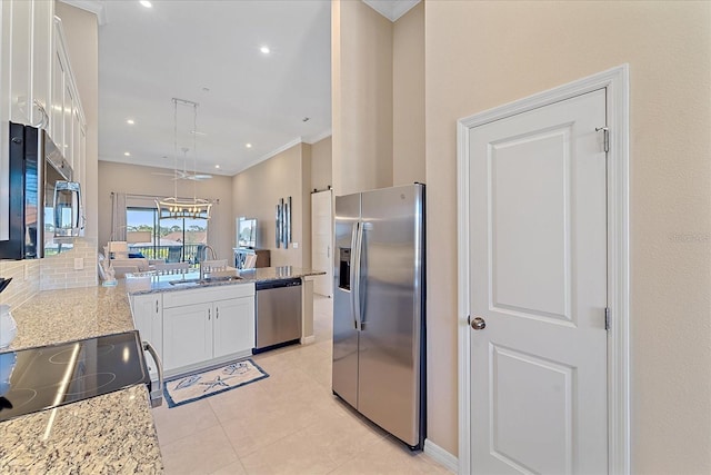 kitchen with backsplash, appliances with stainless steel finishes, a peninsula, white cabinets, and a sink