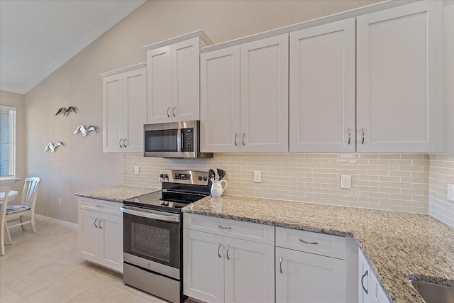 kitchen with light stone countertops, lofted ceiling, light tile patterned floors, decorative backsplash, and stainless steel appliances