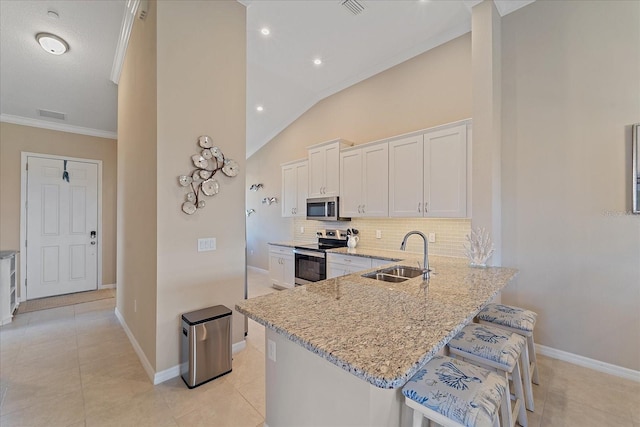 kitchen with a sink, white cabinets, light stone counters, and stainless steel appliances