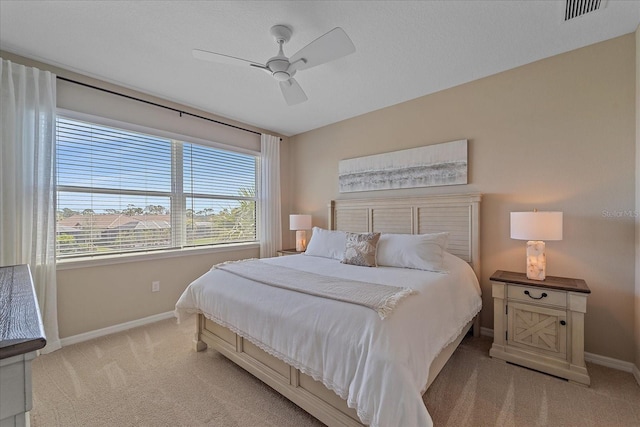 bedroom featuring ceiling fan, light colored carpet, visible vents, and baseboards