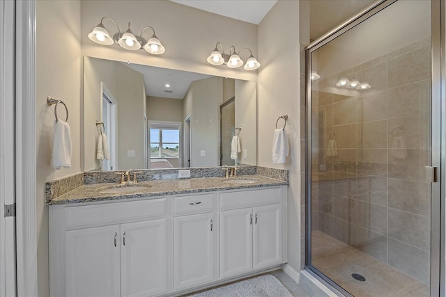 bathroom featuring double vanity, a stall shower, and a sink