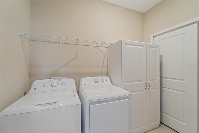 clothes washing area with washing machine and clothes dryer and cabinet space