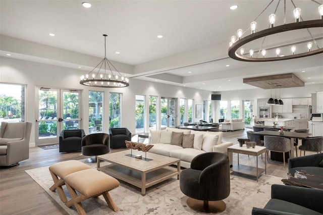 living area with light wood finished floors, recessed lighting, french doors, and an inviting chandelier