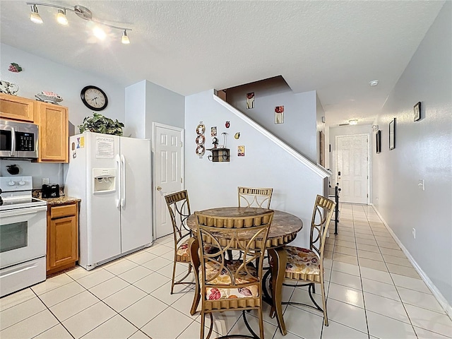 dining space with light tile patterned floors, baseboards, and a textured ceiling