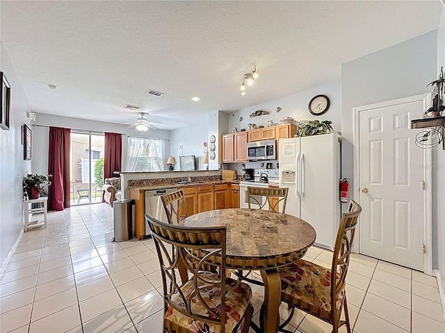 dining space featuring light tile patterned flooring, visible vents, a textured ceiling, and a ceiling fan