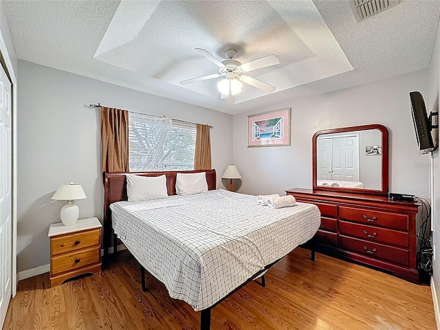 bedroom featuring wood finished floors, visible vents, and a textured ceiling