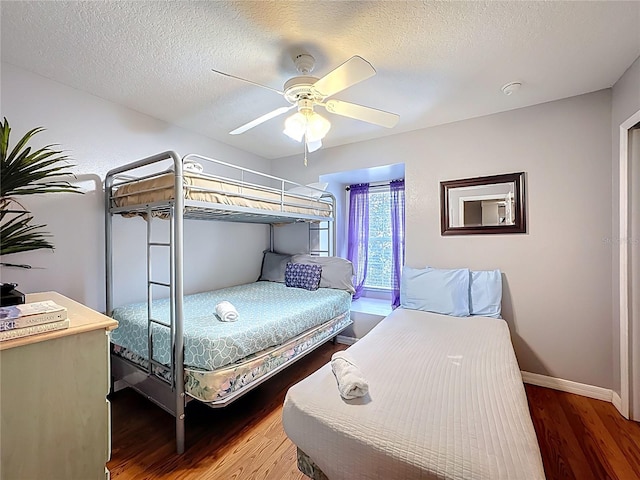 bedroom featuring baseboards, a textured ceiling, ceiling fan, and wood finished floors