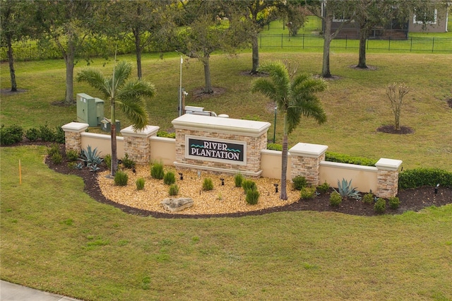 community / neighborhood sign featuring a yard and fence