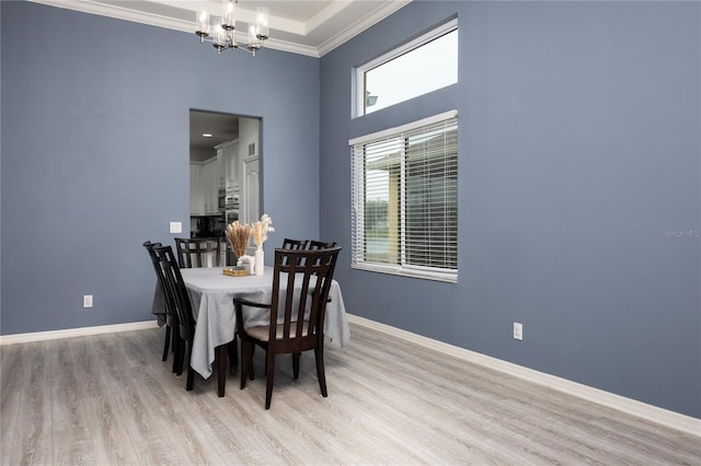 dining space with light wood-style floors, baseboards, a notable chandelier, and ornamental molding