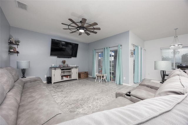 living room with visible vents, plenty of natural light, baseboards, and ceiling fan with notable chandelier