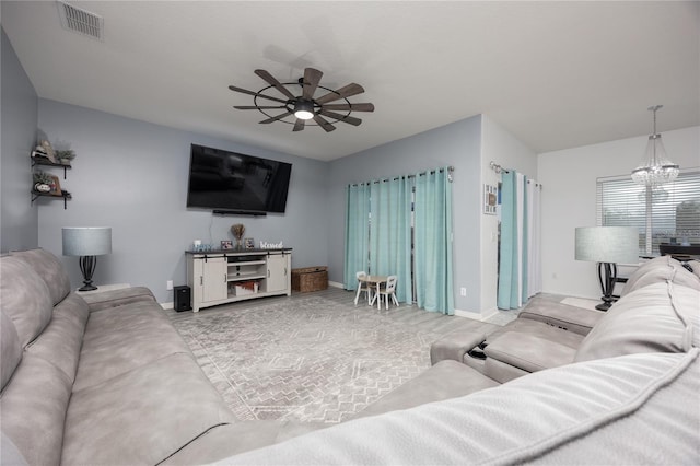 living area with visible vents, baseboards, and ceiling fan with notable chandelier