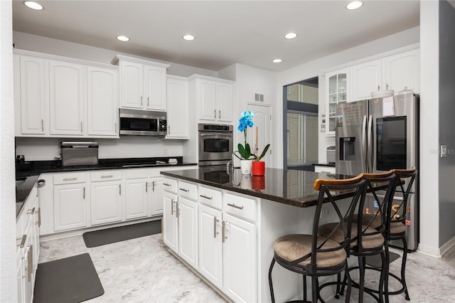 kitchen with a kitchen island, recessed lighting, appliances with stainless steel finishes, a breakfast bar area, and white cabinets