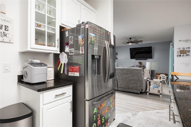 kitchen with stainless steel refrigerator with ice dispenser, white cabinetry, dark stone counters, glass insert cabinets, and ceiling fan