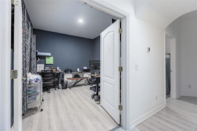 office area featuring wood finished floors, arched walkways, and baseboards