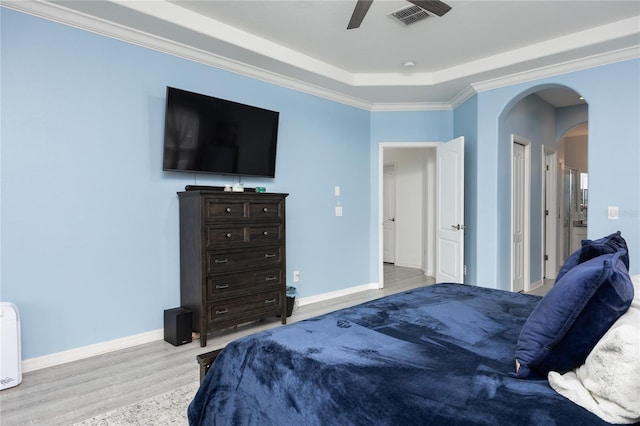 bedroom featuring wood finished floors, visible vents, baseboards, arched walkways, and crown molding