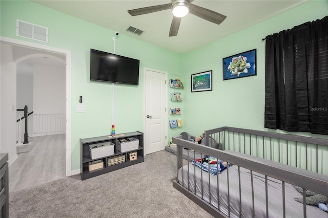 bedroom featuring a nursery area, carpet, visible vents, and arched walkways