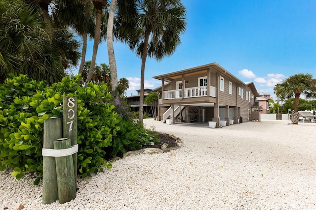 rear view of property featuring stairs, a carport, covered porch, and driveway