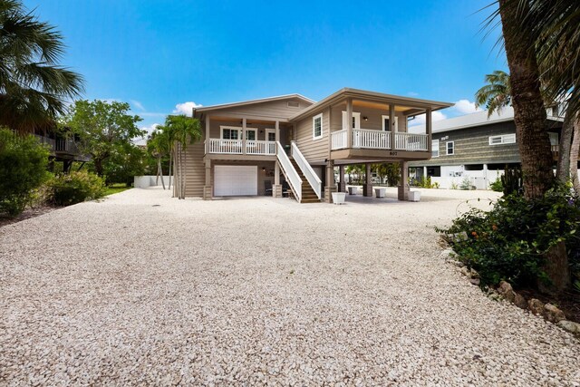 rear view of house featuring stairs, a porch, an attached garage, and driveway