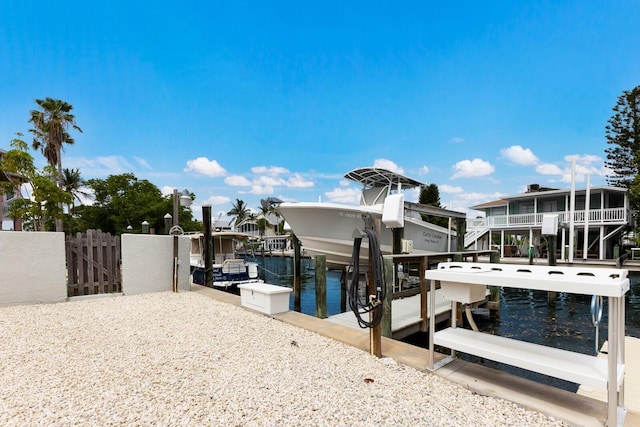 view of dock featuring a water view, boat lift, and fence