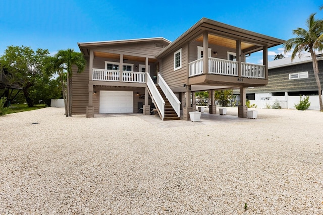 exterior space featuring covered porch, an attached garage, stairs, and driveway