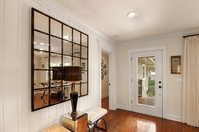 doorway with baseboards, wood finished floors, and ornamental molding